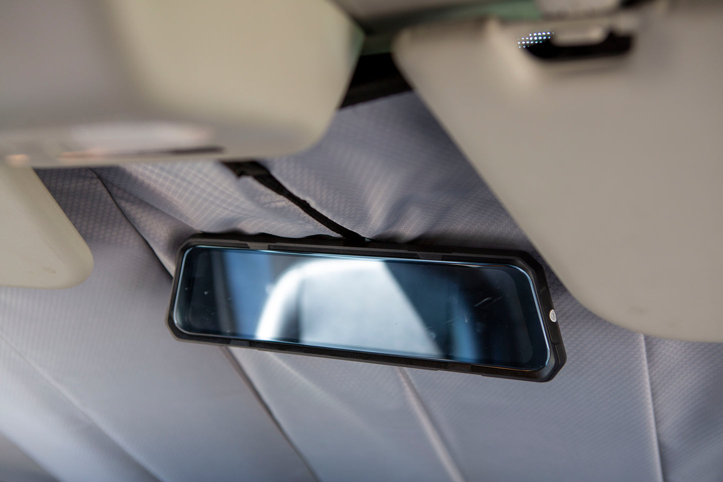 Image showing the window cover securely tucked behind the rearview mirror in a camper van, demonstrating a snug and seamless fit.