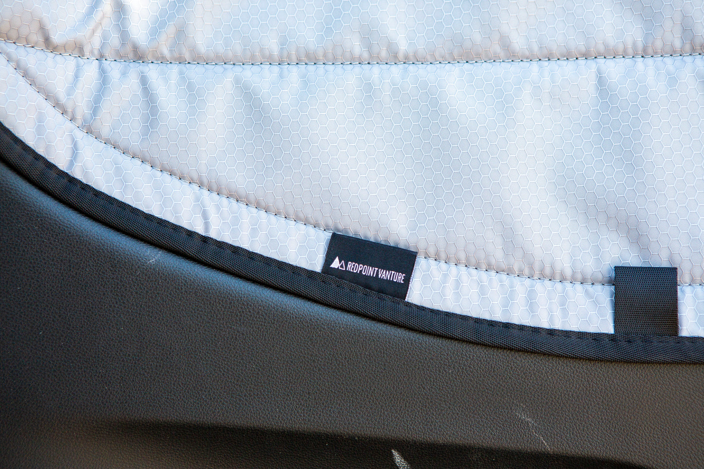 Close-up image of the Redpoint Van Parts logo tag on the window cover, highlighting its high-quality material and precise design for a secure, seamless fit on the window.