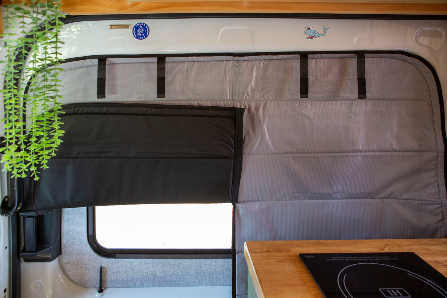 Image of the cover seamlessly attached to a sliding door window in a camper van, with the left panel’s bottom flipped up, showcasing a perfect fit, sleek installation, and flexibility to peek out while the cover is on.