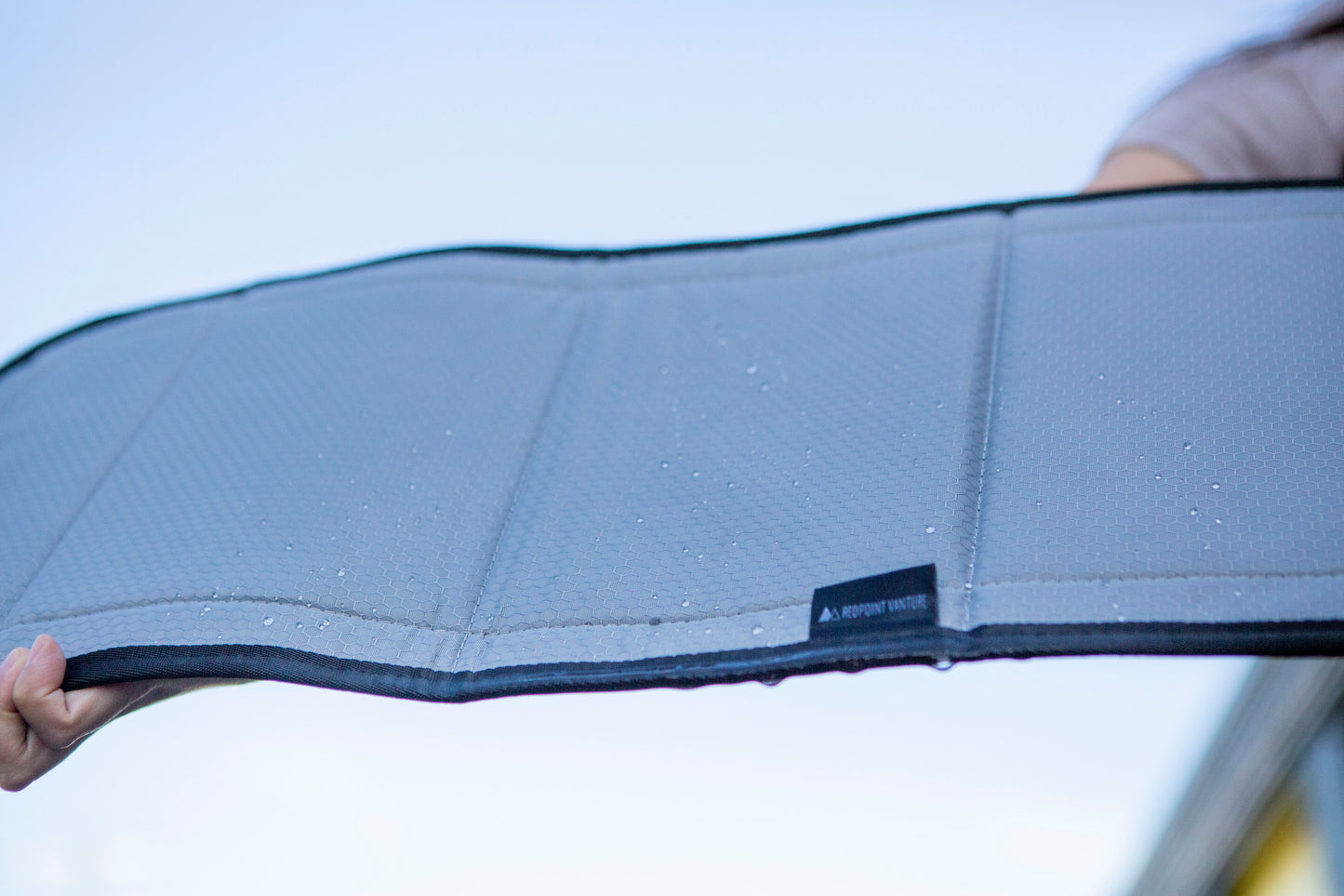 Image of the window cover after water has poured over it, with water droplets remaining on its dry surface, showcasing its water-resistant feature.