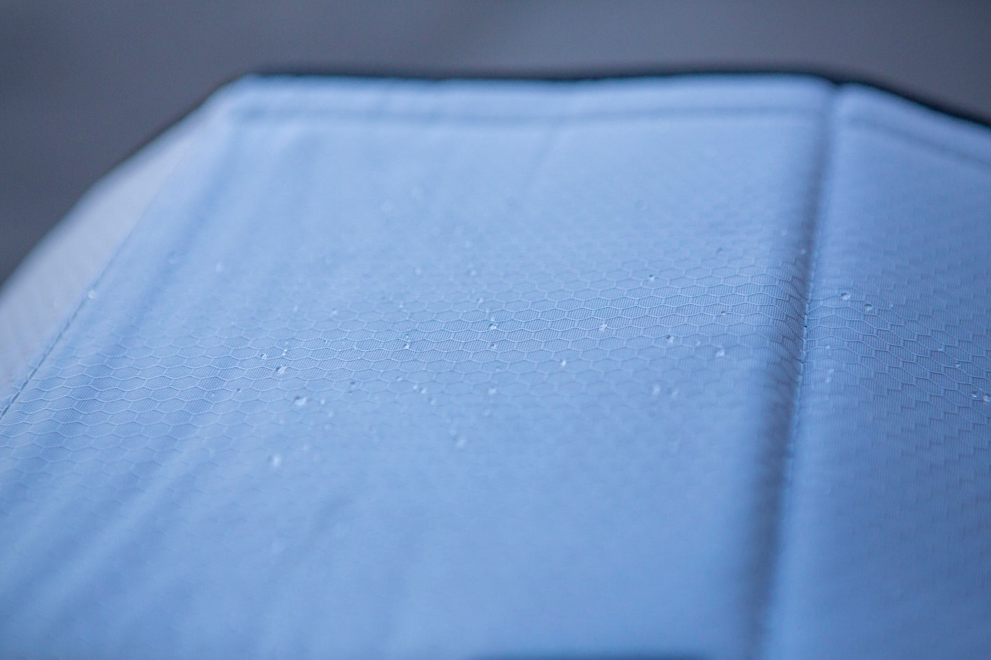 Close-up image of the window cover after water has poured over it, with water droplets remaining on its dry surface, showcasing its water-resistant feature.